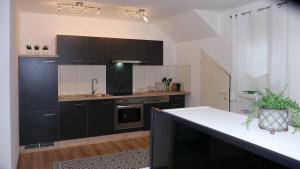eine Küche mit schwarzen Schränken und einer weißen Arbeitsplatte in der Unterkunft Ferienwohnung Philipp in Bartholomäberg