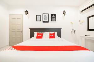 a bedroom with a white bed with red pillows at Super OYO 89486 Kulim Inn in Kulim