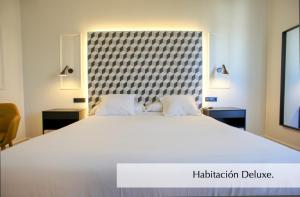 a white bed with a black and white bedspread at Hotel Montermoso in Aranda de Duero