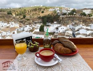 una mesa con una taza de café y un plato de pan en La Casa de la Lela, en Setenil