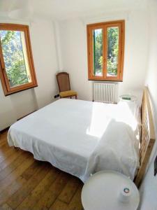 a bedroom with a large white bed with two windows at Villa Olivari - apt la Salvia in San Rocco