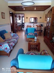 uma sala de estar com sofás azuis e uma mesa em Ti Laura Praia em Praia da Barra