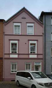 Uma casa cor-de-rosa com uma carrinha estacionada em frente. em SK Apartments - Liborius em Gelsenkirchen