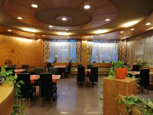 a restaurant with tables and chairs and plants at Hotel du Stand in Martigny-Ville