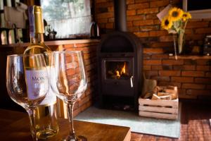 a bottle of wine and two glasses on a table with a fireplace at Domek pod Klonem in Żary