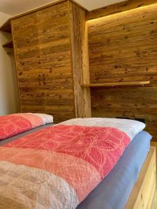 two beds in a room with wooden walls at Ferienwohnungen am Kranzbach FeWo2 in Krün