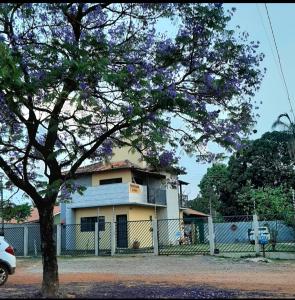 a house with a tree in front of a fence at Pousada Luar in Chapada dos Guimarães