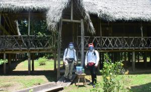 dos personas con máscaras delante de una cabaña en Lodge Jungle Wolf Expeditions, en Yucuruche