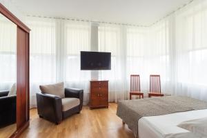 
a living room with a flat screen tv and a chair at Hotel Villa Wesset in Pärnu
