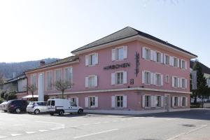 a pink building with cars parked in front of it at Landgasthof Hirschen in Diegten