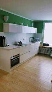 una cucina con armadietti bianchi e pavimenti in legno di Bed and Pool a Oberursel