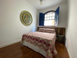 um quarto com uma cama com um cobertor e uma janela em Pousada Travessias em Tiradentes