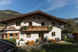 a white house with a balcony with flowers on it at DAS "Bergzeit" - Appartements in Wagrain