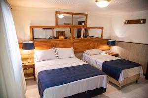a hotel room with two beds and a mirror at Pousada Dom Petrópolis in Petrópolis