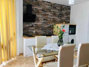 une salle à manger avec une table en verre et des chaises blanches dans l'établissement Flora Apartments Sarande, à Saranda