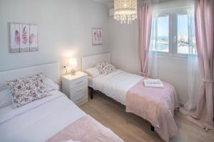 1 dormitorio blanco con 2 camas y ventana en Apartamento Fenicia con aparcamiento incluido Vistas al mar, en Cádiz