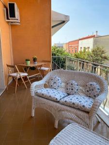 a wicker couch on a balcony with a table at Le Fresie B&B in SantʼAntìoco