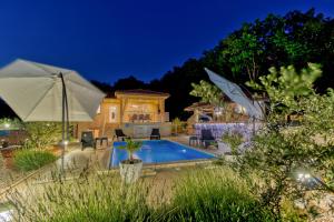 a house with a swimming pool and an umbrella at Villa Sole in Omišalj