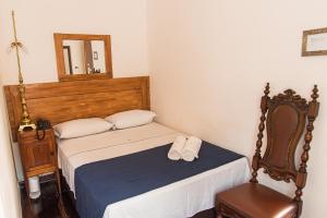 um pequeno quarto com uma cama e um espelho em Pousada Dom Petrópolis em Petrópolis