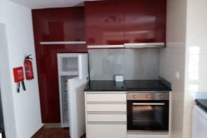 a small kitchen with red cabinets and a stove at Casas da Nazaré2 in Ponte de Lima