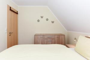 a bedroom with a white bed and a wooden cabinet at Ferienwohnung Teezeit in Neuharlingersiel