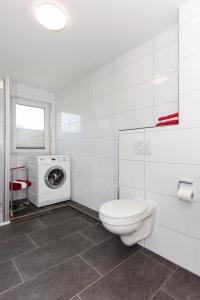 a bathroom with a toilet and a washing machine at Ferienwohnung Teezeit in Neuharlingersiel +46 photos