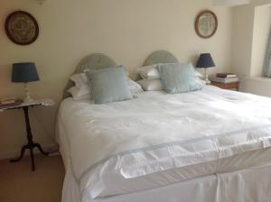 a white bed with a white comforter and pillows at The Coach House in Ross on Wye