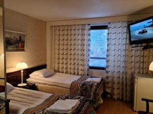 Habitación de hotel con 2 camas y TV de pantalla plana. en Hotelli Sandels, en Siilinjärvi