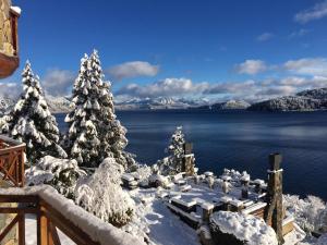 a winter view of a lake with snow covered trees at Lirolay apartments in San Carlos de Bariloche