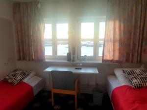 Pokój z 2 łóżkami, biurkiem i oknami w obiekcie Hotel Kulusuk w Kulusuk