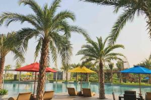 a pool with palm trees and chairs and umbrellas at Studio Apartment - Gold Coast PIK, Jakarta Utara in Jakarta