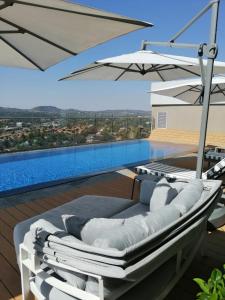 a white lounge chair with an umbrella on a balcony at Menlyn Maine Luxury Apartments in Pretoria