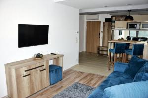 a living room with a blue couch and a tv on a wall at Portofino Apartman in Sárvár