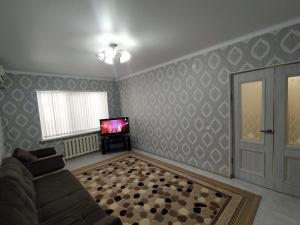 ein Wohnzimmer mit einem Sofa und einem TV in der Unterkunft 2 комнатная в микрорайоне Шугыла in Qysylorda
