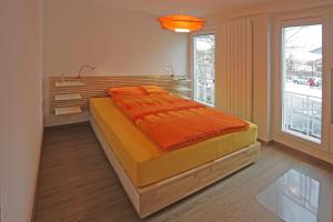 ein Schlafzimmer mit einem großen Bett mit einer orangefarbenen Decke in der Unterkunft Landgasthof Hirschen in Diegten