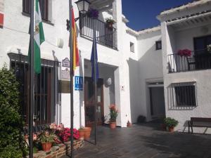 a white building with flags in front of it at Villa Turistica de Bubion in Bubión