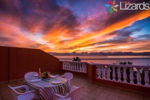 una mesa y sillas en un balcón con puesta de sol en 7Lizards - Ocean View Apartments, en Puerto de Santiago