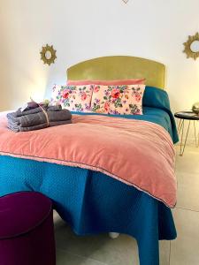 a bedroom with a blue bed with colorful pillows at Petit Rêve in LʼIsle-sur-la-Sorgue
