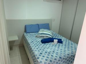 a small bed with a blue comforter and a cup on it at Flat - Brookfield Towers in Goiânia