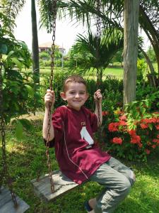 a young boy sitting on a swing at Muangway Garden Ville in Ban Phon Thong