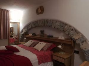 a bedroom with a large bed with a stone wall at Haus Green & Spa Angelika Trentino in Lavarone