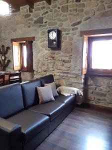 sala de estar con sofá de cuero y pared de piedra en Casa do Pelourinho, en Rebordainhos