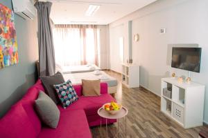 salon z różową kanapą i telewizorem w obiekcie Ermou Downtown Studios by Hospitality Box w Atenach