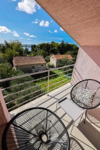 a balcony with two chairs and a view of the countryside at Apartment and Rooms Santini in Sveti Filip i Jakov