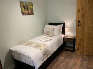 a small bedroom with a bed and a night stand at Pumping Station Holidays in Cinderford