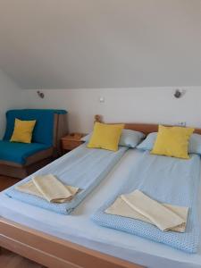 two beds with yellow and blue pillows on them at House Matijević Šimić in Grabovac