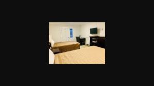 Habitación de hotel con 2 camas, escritorio y 1 dormitorio en Traveler's Motel Penticton en Penticton