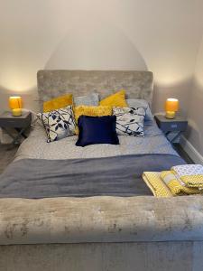 ein Schlafzimmer mit einem großen Bett mit gelben und blauen Kissen in der Unterkunft Cambridge Villas Private Studio Lytham St Annes in Saint Annes on the Sea