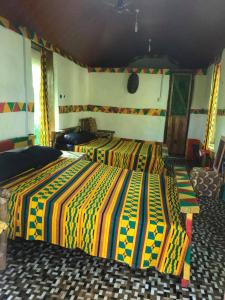Green Zion Garden في Butre: غرفة نوم مع سريرين مع بطانيات ملونة