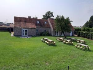 un grupo de mesas de picnic frente a un edificio en Kalmthoutse Hoeve en Kalmthout